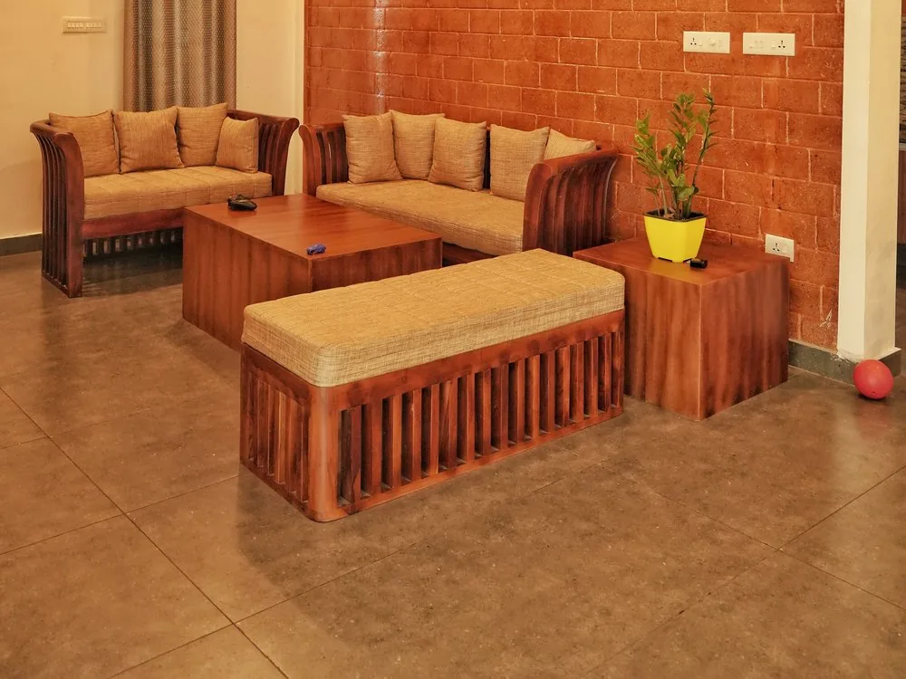 Compact 2 BHK living room with terracotta brick feature wall and custom wooden seating, designed by interior designers in Bangalore