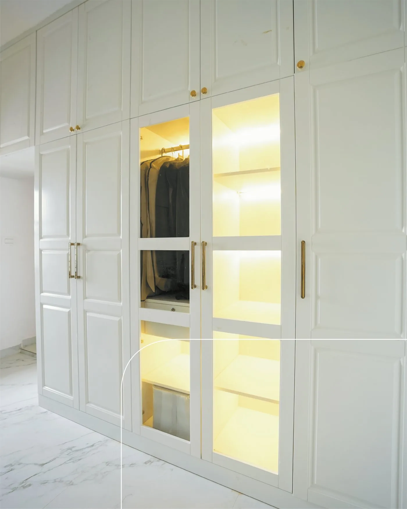 Glass-front wardrobe section with warm integrated lighting