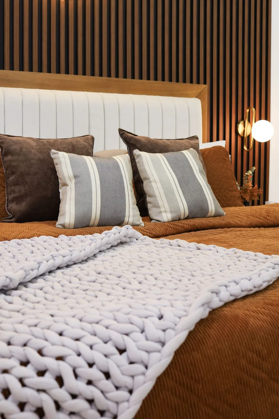 Warm layered bedroom with panelled headboard - 2 BHK bedroom idea