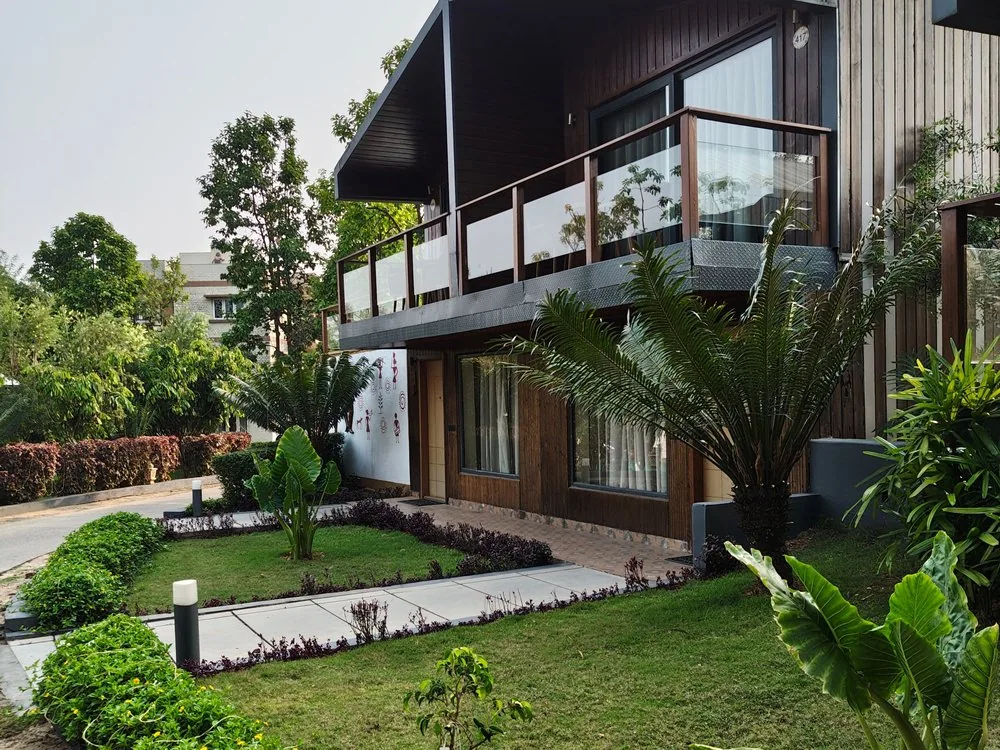 Contemporary villa exterior with wood cladding and Warli mural, designed by interior designers in Bangalore